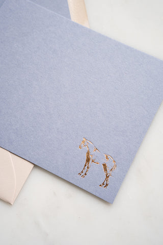 Photo of a lavender correspondence card with a gold foil stamped design featuring a drawing of a horse standing by equine artist Danielle Demers.