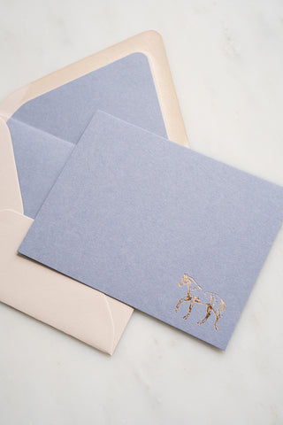 Photo of a lavender correspondence card with a gold foil stamped design featuring a drawing of a horse walking by equine artist Danielle Demers.