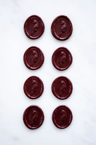 Photo of a set of eight deep burgundy wax seals featuring a three-dimensional intaglio impression of a fox designed by equine artist Danielle Demers