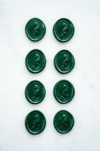 Photo of a set of eight metallic emerald green wax seals featuring a three-dimensional intaglio impression of a fox designed by equine artist Danielle Demers