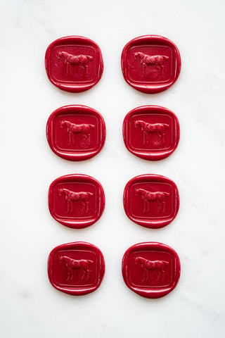 Photo of a set of eight metallic Christmas red wax seals featuring a three-dimensional intaglio impression of a horse designed by equine artist Danielle Demers