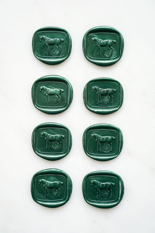 Photo of a set of eight metallic emerald green wax seals featuring a three-dimensional intaglio impression of a horse designed by equine artist Danielle Demers
