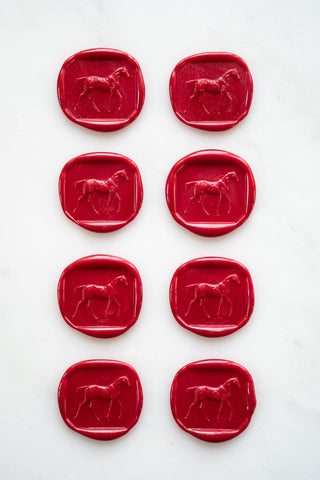 Photo of a set of eight metallic Christmas red wax seals featuring a three-dimensional intaglio impression of a horse designed by equine artist Danielle Demers