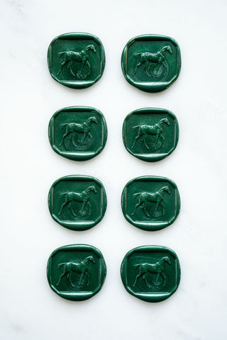 Photo of a set of eight metallic green wax seals featuring a three-dimensional intaglio impression of a horse designed by equine artist Danielle Demers