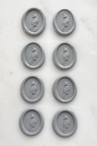 Photo of a set of eight grey wax seals featuring fox designs created by equine artist Danielle Demers