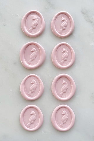 Photo of a set of eight petal pink wax seals featuring fox designs created by equine artist Danielle Demers