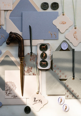 A collection of equestrian stationery arranged on a marble desk and styled with an antique horse letter opener. Featuring horse, fox and hare correspondence cards, gift tags and wax seals by equine artist Danielle Demers.