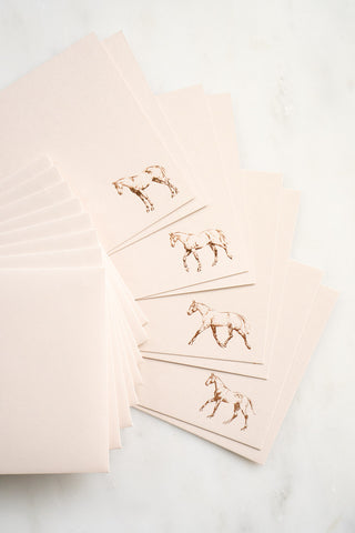 Photo of a set of 8 copper foil stamped correspondence cards featuring drawings of horses standing, walking, trotting, and cantering by equine artist Danielle Demers