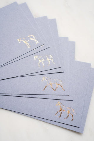 Photo of a set of 8 gold foil stamped correspondence cards featuring drawings of horses standing, walking, trotting, and cantering by equine artist Danielle Demers