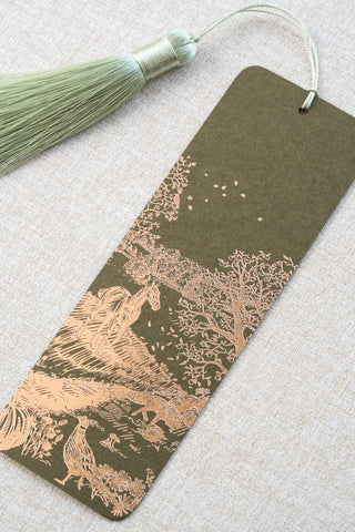 A foil stamped bookmark featuring a countryside autumn scene with a horse, fox, pumpkins, pheasant, and crow. Printed in copper foil on a mossy green card stock and finished with a light celadon green tassel.