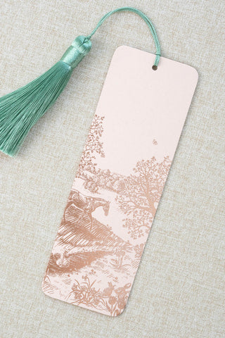 A foil stamped bookmark featuring a countryside spring scene with a horse, swan, rabbits, butterflies and flowers. Printed in rose gold foil on a light peach pink card stock and finished with a light turquoise tassel.