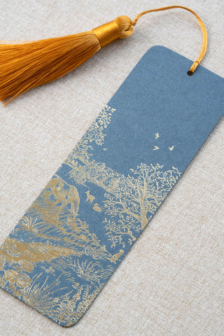 A foil stamped bookmark featuring a countryside summer scene with a horse, flowers, deer, a stoat, birds, butterflies and a bee. Printed in gold foil on French Blue card stock and finished with a Gamboge yellow tassel.