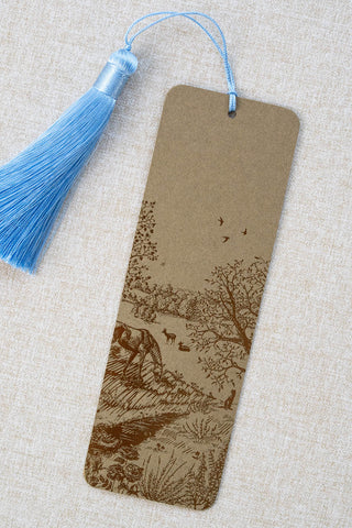A foil stamped bookmark featuring a countryside summer scene with a horse, flowers, deer, a stoat, birds, butterflies and a bee. Printed in bronze foil on walnut card stock and finished with a sky blue tassel.