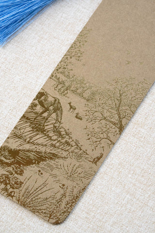 A foil stamped bookmark featuring a countryside summer scene with a horse, flowers, deer, a stoat, birds, butterflies and a bee. Printed in bronze foil on walnut card stock and finished with a sky blue tassel.