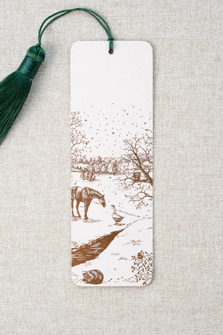 A foil stamped bookmark featuring a countryside winter scene with a horse, goose, hedgehog, robin and red squirrel. Printed in copper foil on a cream card stock and finished with a deep green tassel.
