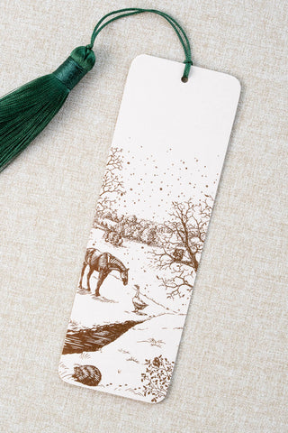 A foil stamped bookmark featuring a countryside winter scene with a horse, goose, hedgehog, robin and red squirrel. Printed in copper foil on a cream card stock and finished with a deep green tassel.