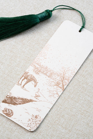 A foil stamped bookmark featuring a countryside winter scene with a horse, goose, hedgehog, robin and red squirrel. Printed in copper foil on a cream card stock and finished with a deep green tassel.