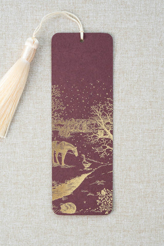 A foil stamped bookmark featuring a countryside winter scene with a horse, goose, hedgehog, robin and red squirrel. Printed in gold foil on a deep maroon card stock and finished with a cream tassel.