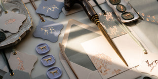 An arrangement of equestrian stationery: horse, hare and fox gift tags, correspondence cards and wax seals on a marble desk.