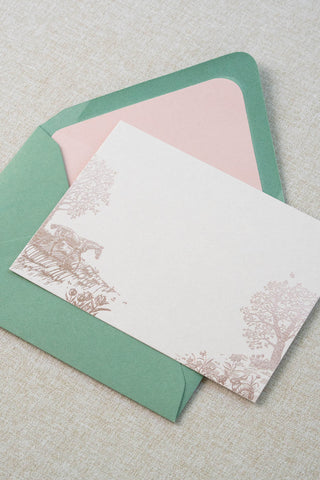 Foil stamped correspondence card featuring a spring scene with a horse, rabbits, tulips, daffodils, trees and butterflies. Rose gold foil design on cream card stock with a green envelope lined in a blush pink liner.