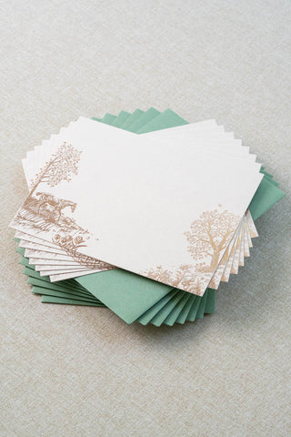 Set of eight foil stamped correspondence card featuring a spring scene with a horse, rabbits, tulips, daffodils, trees and butterflies. Rose gold foil design on cream card stock with a green envelope lined in a blush pink liner.