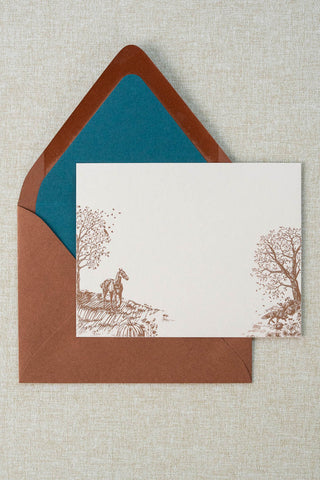 Foil stamped correspondence card featuring an autumn scene with a horse, fox, pumpkins, a pheasant, trees and a crow. Rose gold foil design on cream card stock with a sienna brown envelope lined in a deep teal liner.