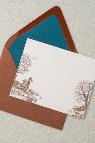 Foil stamped correspondence card featuring an autumn scene with a horse, fox, pumpkins, a pheasant, trees and a crow. Rose gold foil design on cream card stock with a sienna brown envelope lined in a deep teal liner.