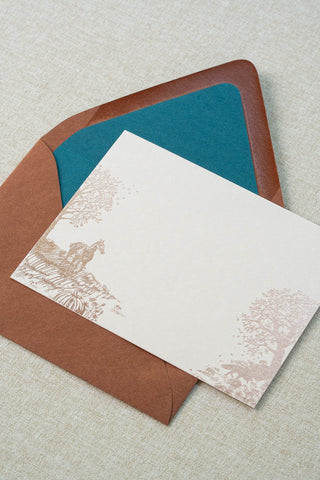 Foil stamped correspondence card featuring an autumn scene with a horse, fox, pumpkins, a pheasant, trees and a crow. Rose gold foil design on cream card stock with a sienna brown envelope lined in a deep teal liner.