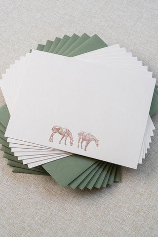 Set of eight cream correspondence cards featuring horse illustrations foil stamped in rose gold. Accompanying medium green envelopes are lined with scalloped-edge dusty blue envelope liners.