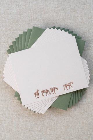 Set of eight cream correspondence cards featuring horse illustrations foil stamped in rose gold. Accompanying medium green envelopes are lined with scalloped-edge dusty blue envelope liners.
