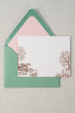 Foil stamped correspondence card featuring a spring scene with a horse, rabbits, tulips, daffodils, trees and butterflies. Rose gold foil design on cream card stock with a green envelope lined in a blush pink liner.