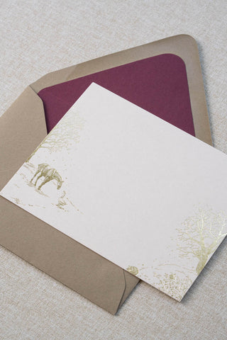 Foil stamped correspondence card featuring a winter scene with a horse, goose, hedgehog, robin, trees and snow. Gold foil design on cream card stock with a taupe envelope lined in a deep cranberry liner.