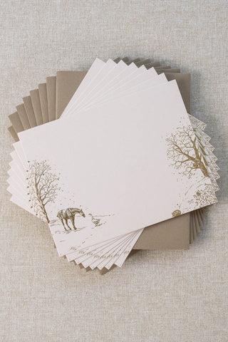 Set of eight foil stamped correspondence cards featuring a winter scene with a horse, goose, hedgehog, robin, trees and snow. Gold foil design on cream card stock with a taupe envelope lined in a deep cranberry liner.