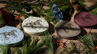 Hand-painted and block printed ceramic horse motif ornaments featuring a horse cantering through snowflakes