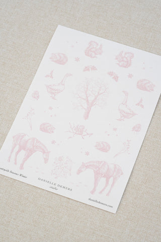 Danielle Demers washi paper sticker sheet on a light beige textured fabric background. The sticker sheet features delicate pink illustrations of horses, countryside animals, and flowers.