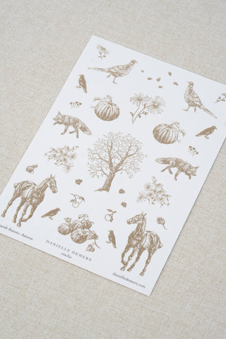 Danielle Demers washi paper sticker sheet on a light beige textured fabric background. The sticker sheet features delicate taupe brown illustrations of horses, countryside animals, and flowers.
