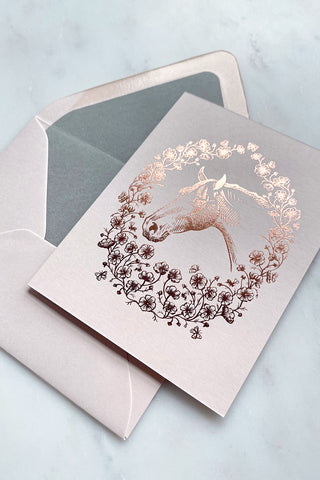 Photo of a rich copper metallic foil stamped design, featuring a drawing of a horse in a wreath of cosmos flowers, bees and butterflies, on cream card stock by equine artist Danielle Demers.
